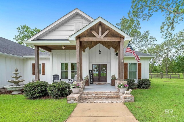 view of front of house featuring a front lawn, a porch, and french doors