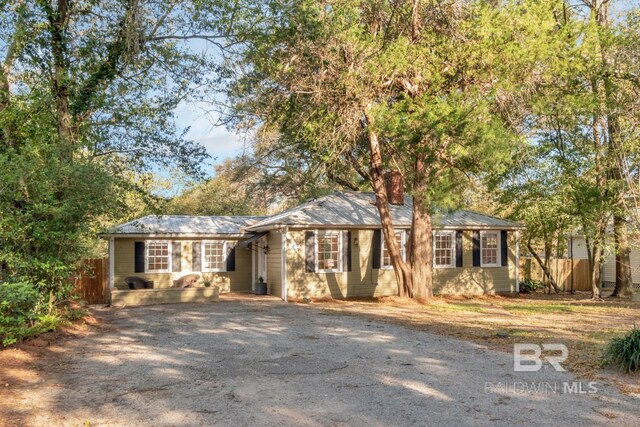 ranch-style house featuring driveway, fence, and a chimney