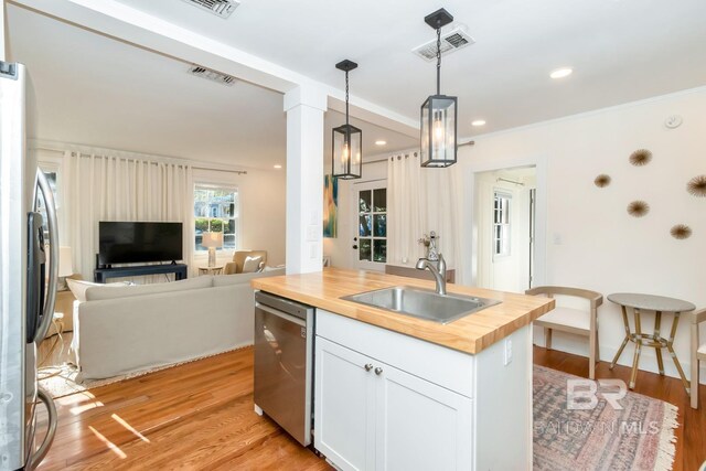 kitchen with visible vents, wood counters, stainless steel appliances, a sink, and open floor plan