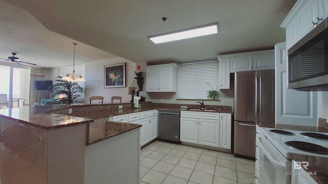 kitchen featuring dark stone counters, ceiling fan, kitchen peninsula, stainless steel appliances, and light tile flooring