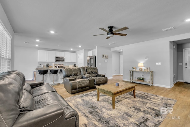 living room featuring ceiling fan and light hardwood / wood-style floors