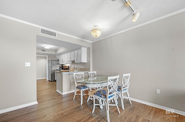 dining space with visible vents, baseboards, wood finished floors, and a textured ceiling