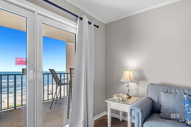 sitting room with baseboards, a beach view, ornamental molding, and a water view