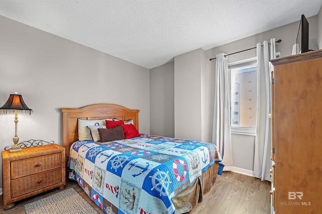 bedroom featuring wood finished floors and a textured ceiling