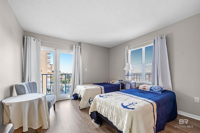 bedroom with wood finished floors, a textured ceiling, access to outside, and multiple windows