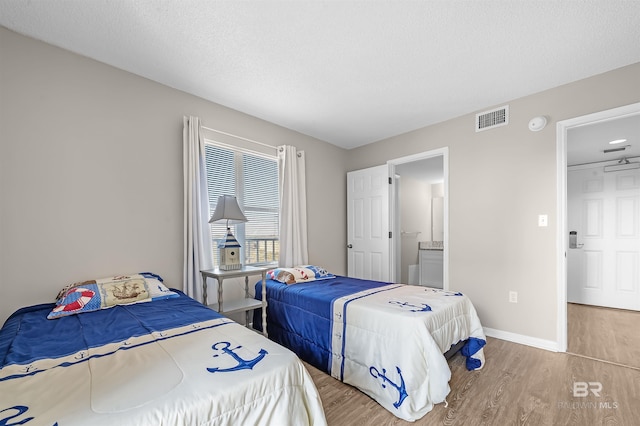 bedroom featuring baseboards, wood finished floors, and visible vents