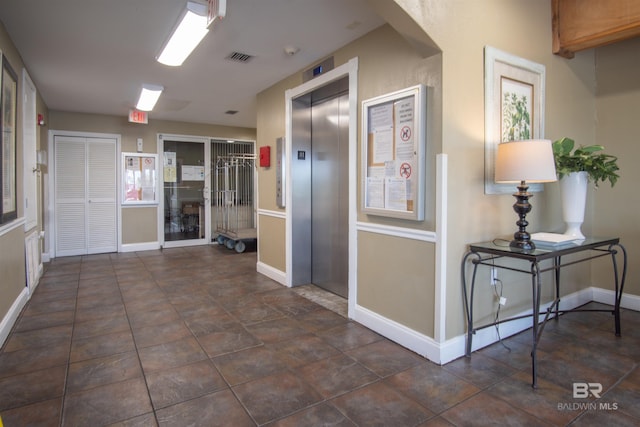 hall featuring visible vents, baseboards, and elevator