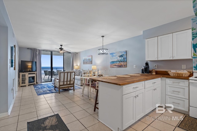 kitchen with white cabinetry, a kitchen breakfast bar, decorative light fixtures, and wood counters