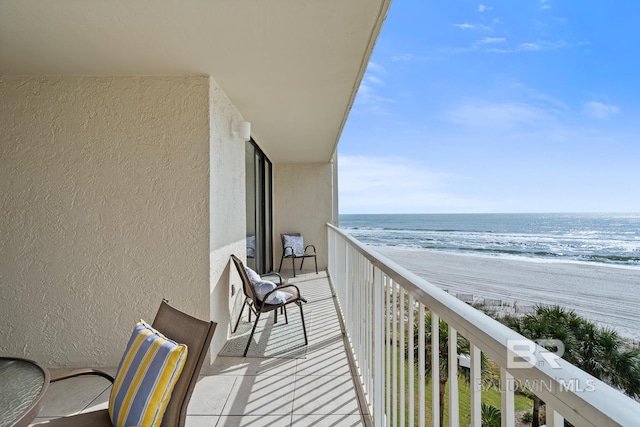 balcony featuring a view of the beach and a water view