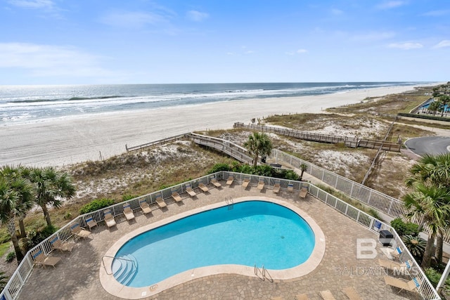 view of pool featuring a patio area, a water view, and a view of the beach