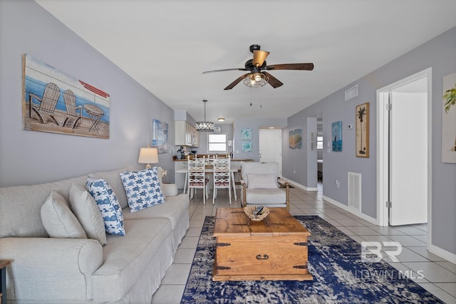 living room featuring tile patterned flooring and ceiling fan with notable chandelier