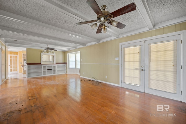 unfurnished living room with beamed ceiling, hardwood / wood-style floors, french doors, a textured ceiling, and ceiling fan