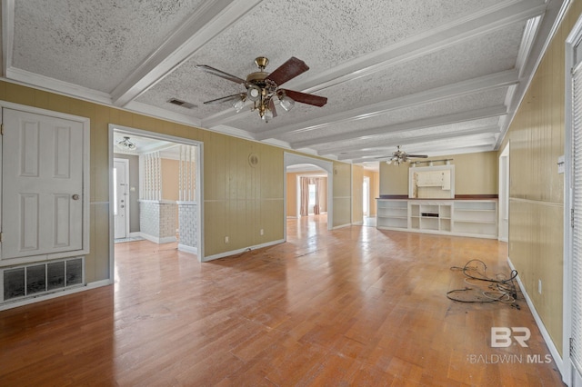 unfurnished living room with a textured ceiling, beam ceiling, ceiling fan, and hardwood / wood-style flooring