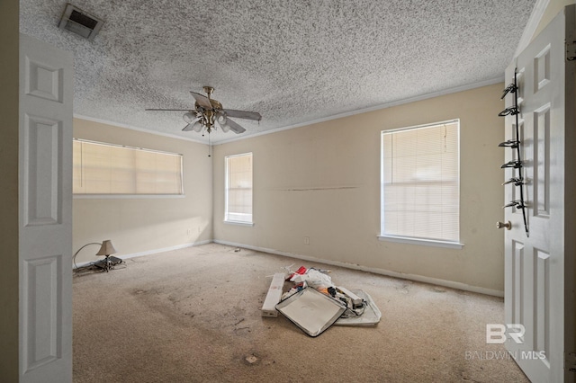 carpeted empty room featuring ornamental molding, a healthy amount of sunlight, and ceiling fan