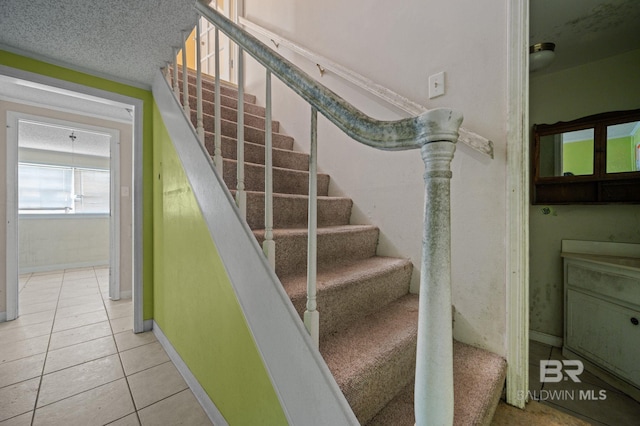 stairway with a textured ceiling and light tile patterned floors