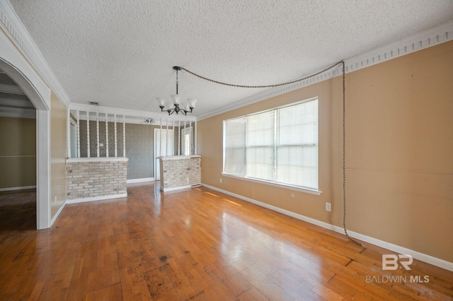 unfurnished living room featuring crown molding, a textured ceiling, hardwood / wood-style flooring, and a notable chandelier