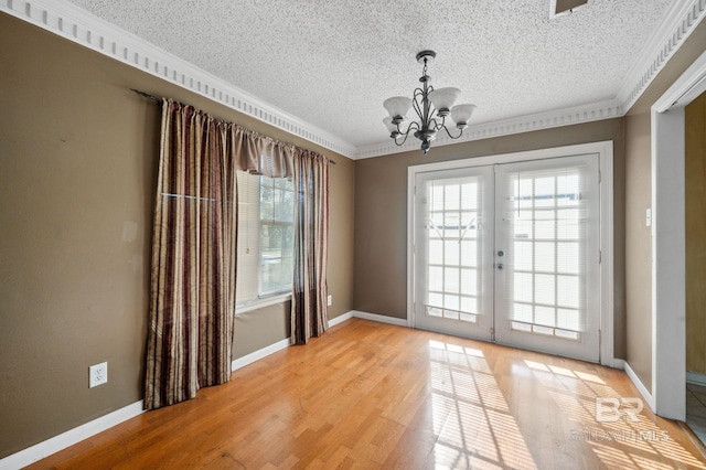 interior space with ornamental molding, a notable chandelier, hardwood / wood-style flooring, and french doors