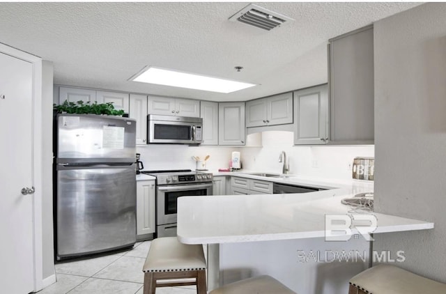 kitchen featuring a sink, gray cabinets, appliances with stainless steel finishes, and visible vents