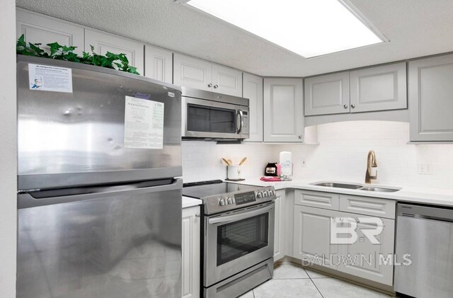 kitchen with light countertops, appliances with stainless steel finishes, gray cabinets, and a sink