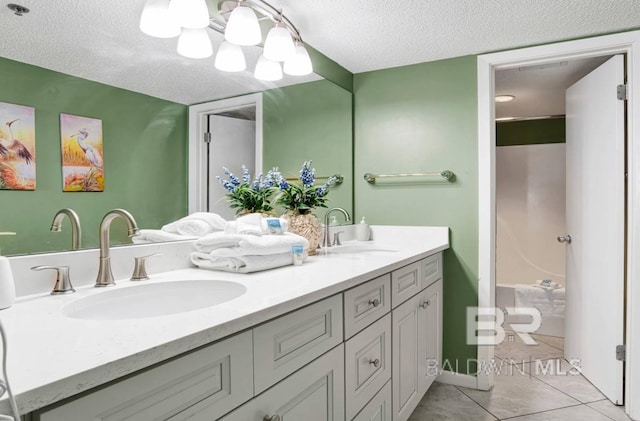 bathroom with a sink, tile patterned floors, double vanity, and a textured ceiling
