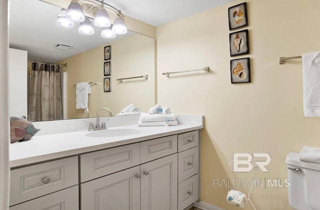 bathroom featuring vanity, visible vents, a textured ceiling, and toilet