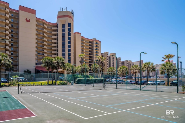view of tennis court with community basketball court and fence