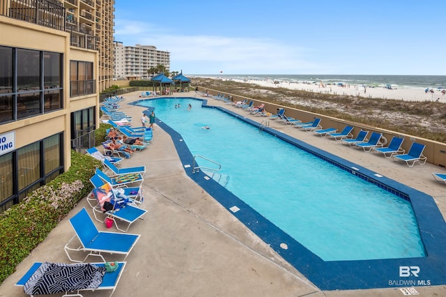 community pool featuring a patio area, a view of the beach, and a water view