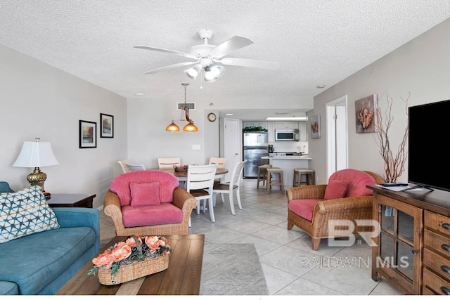 living area featuring visible vents, ceiling fan, light tile patterned floors, and a textured ceiling