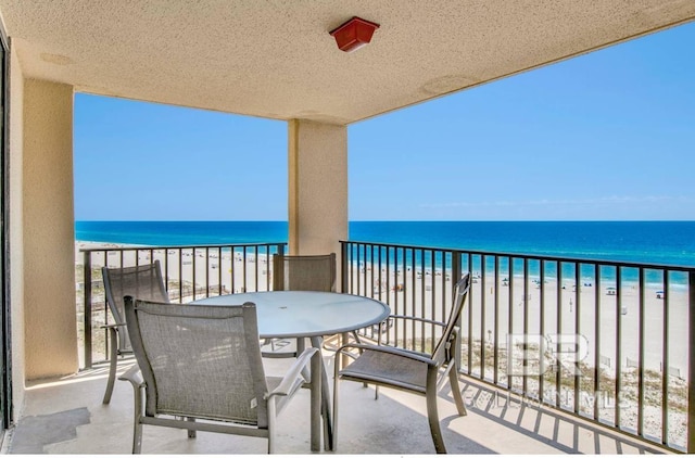 balcony with a water view and a view of the beach