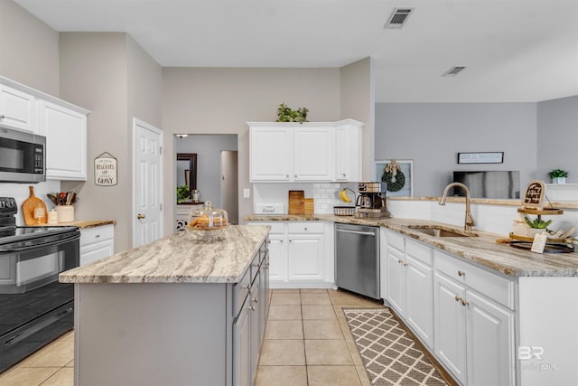 25697 Overlook Dr, Loxley, AL 36551 - kitchen featuring appliances with stainless steel finishes, a sink, light tile patterned floors, decorative backsplash, and a center island