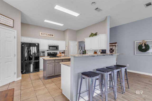 25697 Overlook Dr, Loxley, AL 36551 - kitchen with black appliances, a peninsula, a breakfast bar, and white cabinetry