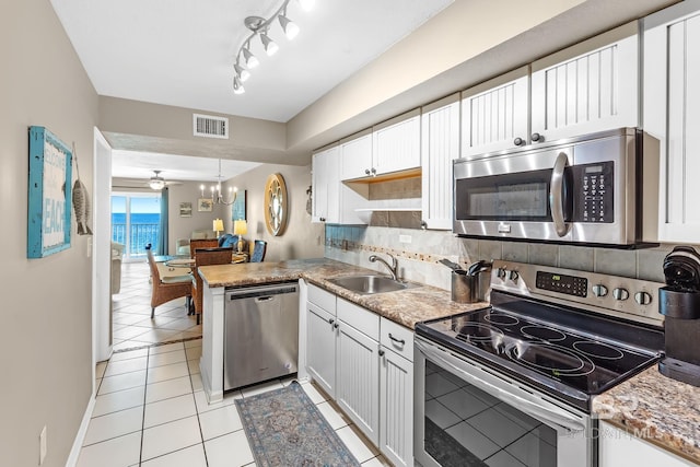 kitchen featuring a peninsula, a sink, visible vents, appliances with stainless steel finishes, and backsplash