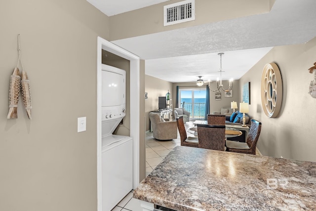 dining area with stacked washer and dryer, light tile patterned floors, visible vents, and an inviting chandelier