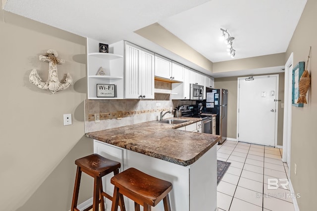 kitchen with a peninsula, backsplash, stainless steel appliances, and a sink