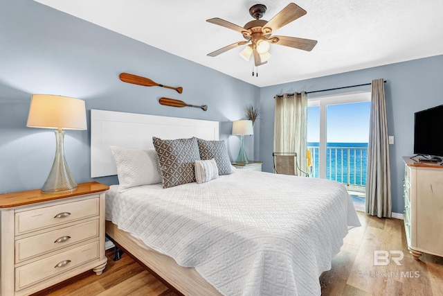 bedroom featuring access to outside, light wood-type flooring, and a ceiling fan