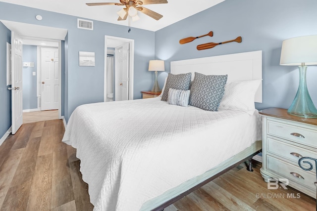 bedroom with ceiling fan, wood finished floors, visible vents, and baseboards