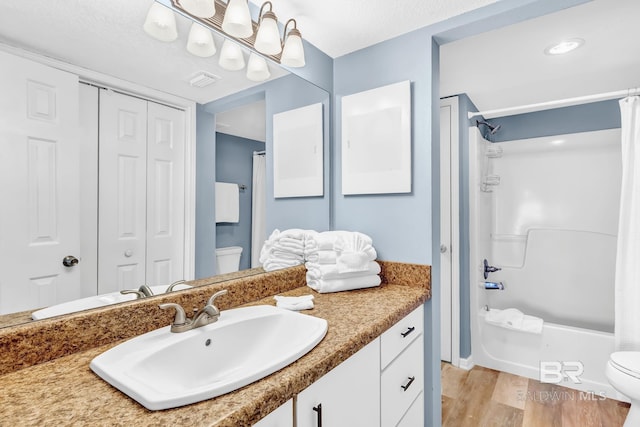 bathroom featuring shower / tub combo with curtain, a closet, toilet, vanity, and wood finished floors