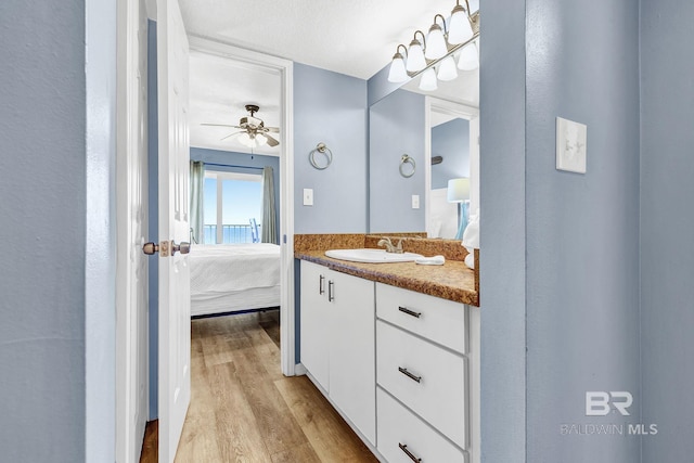 bathroom with vanity, a ceiling fan, connected bathroom, and wood finished floors