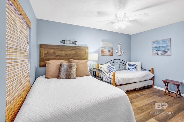 bedroom with ceiling fan, baseboards, and wood finished floors