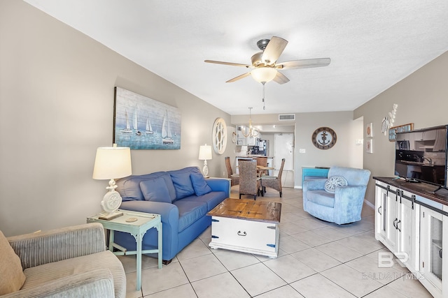 living area featuring visible vents, light tile patterned flooring, a textured ceiling, baseboards, and ceiling fan with notable chandelier