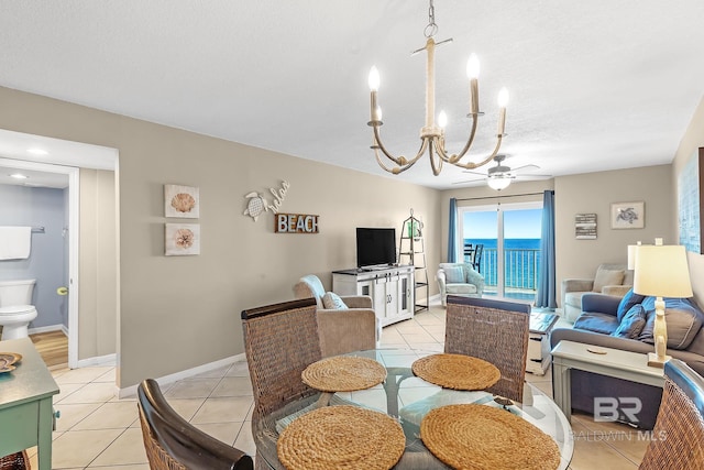 dining area featuring ceiling fan with notable chandelier, a textured ceiling, baseboards, and light tile patterned floors