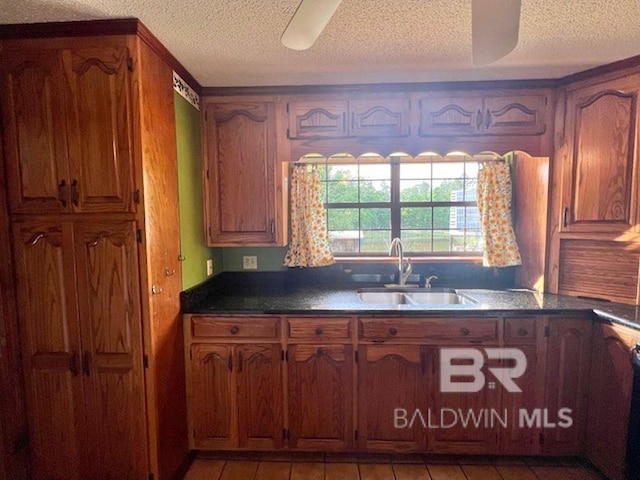 kitchen with a sink, a textured ceiling, and brown cabinets