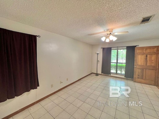 spare room with visible vents, a ceiling fan, a textured ceiling, and light tile patterned floors