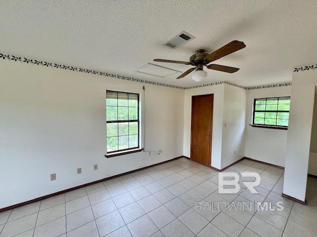 interior space with light tile patterned flooring, a textured ceiling, a ceiling fan, baseboards, and visible vents