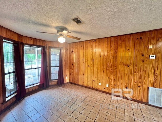 empty room with visible vents, a textured ceiling, ceiling fan, and baseboards