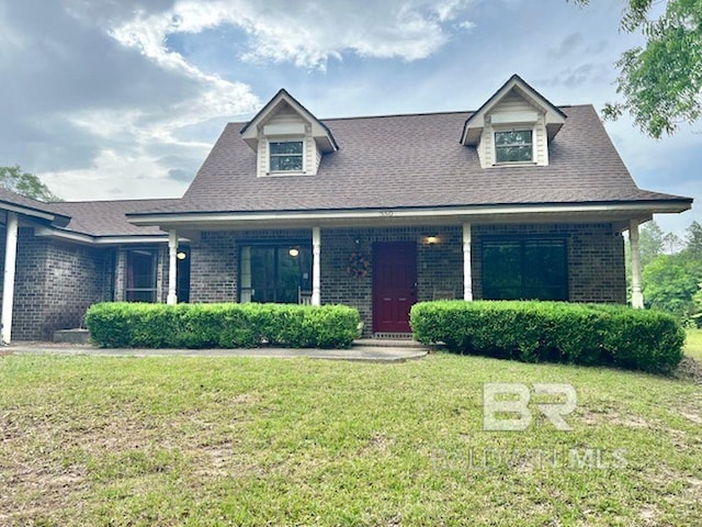 view of front of house with brick siding, a front lawn, roof with shingles, and a porch