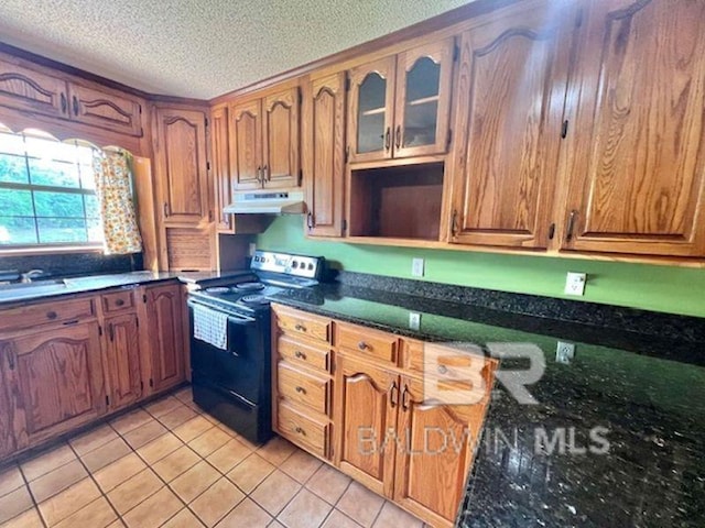 kitchen with brown cabinets, electric range, a textured ceiling, light tile patterned floors, and under cabinet range hood