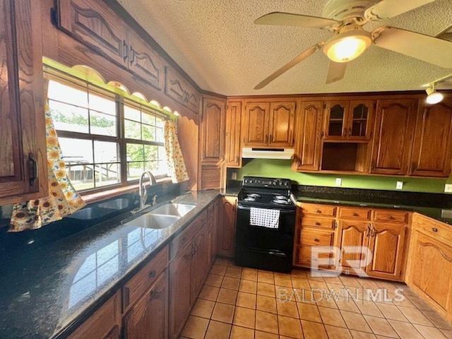 kitchen with a textured ceiling, black range with electric stovetop, a sink, under cabinet range hood, and light tile patterned flooring