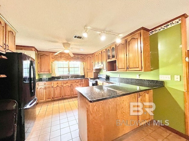 kitchen featuring a textured ceiling, stainless steel range with electric stovetop, freestanding refrigerator, a peninsula, and light tile patterned flooring
