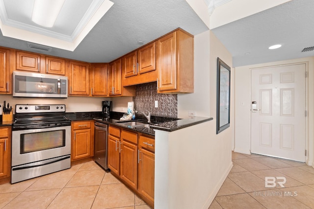 kitchen featuring light tile patterned floors, a tray ceiling, appliances with stainless steel finishes, and a sink